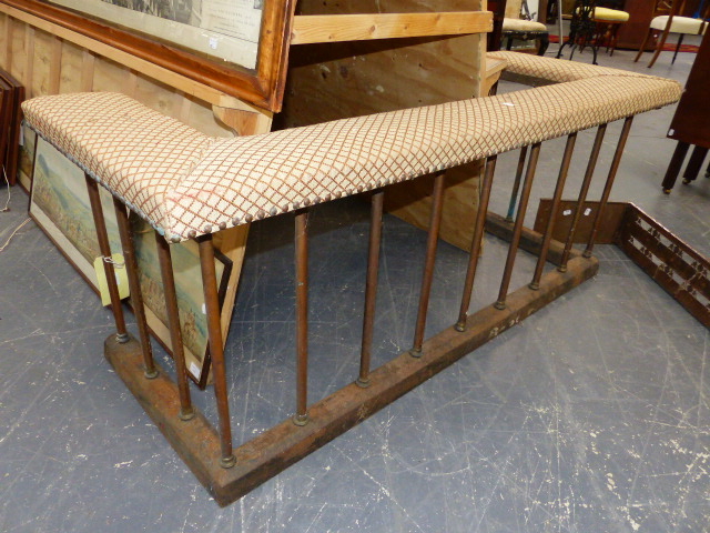 AN ANTIQUE CLUB FENDER WITH UPHOLSTERED TOP RAIL OVER BRASS SUPPORTS ON IRON CURB BASE. 145 x 58 x