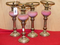 A SET OF FOUR OIL LAMPS, THE FROSTED PINK GLASS RECEIVERS INSERTING INTO OLD SHEFFIELD PLATE