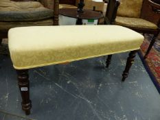 A MAHOGANY DOUBLE STOOL, THE YELLOW DAMASK COVERED SEAT ABOVE TURNED LEGS AND SPINDLE FEET. W.94 x