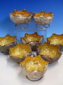 A SET OF EIGHT INDIAN WHITE METAL RING FOOTED PETAL EDGED BOWLS WITH VINE CHASED EXTERIORS AND