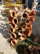 A POT STAND HOLDING VARIOUS TERRACOTTA PLANT POTS