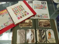 A VINTAGE POSTCARD ALBUM A SAFARI STAMP ALBUM, AND ONE OTHER STAMP ALBUM.