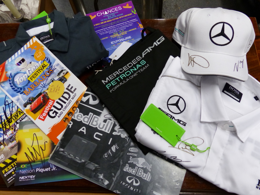 A COLLECTION OF PROGRAMMES AND CLOTHING SIGNED BY LEWIS HAMILTON, NELSON PIQUET, MARK WEBBER AND