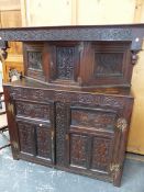 AN 18th.C.OAK COURT CUPBOARD WITH SINGLE UPPER CARVED PANEL DOOR OVER PAIR OF THREE PANEL DOORS TO