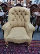 A VICTORIAN BUTTON BACK ARMCHAIR WITH TURNED FRONT LEGS ON CERAMIC CASTERS.