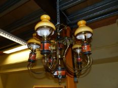 A BRASS FIVE LIGHT CHANDELIER WITH PEACH COLOURED GLASS SHADES AND CLEAR GLASS CHIMNEYS.