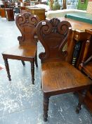 A PAIR OF VICTORIAN OAK HALL CHAIRS WITH CARVED BACK PANELS, PLANK SEATS AND TURNED LEGS. (2)