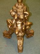 AN ANTIQUE CARVED AND GILT TORCHERE WITH FLUTED COLUMN SUPPORTED BY THREE PUTTI AND FOLIATE FEET.