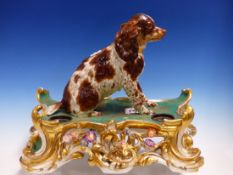 A JACOB PETTIT INKSTAND SURMOUNTED BY A SEATED BROWN AND WHITE SPANIEL, GILT ROCOCO SCROLLS