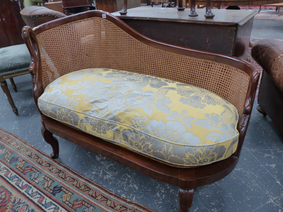 A GOOD QUALITY FRENCH STYLE HARDWOOD AND CANED SMALL CHAISE LONGUE WITH SWAN FORM ARMS AND FEATHER