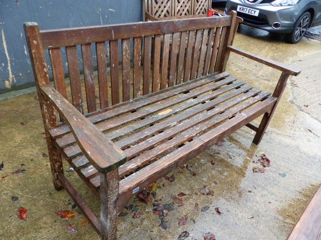 A TEAK GARDEN BENCH WITH PLAIN SLAT BACK.