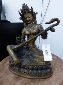 A TIBETAN BRONZE FIGURE OF SARASWATI, THE MUSIC GODDESS SEATED ON A DOUBLE LOTUS THRONE PLAYING A