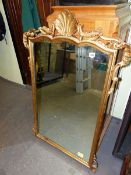 A VINTAGE VICTORIAN STYLE RECTANGULAR MIRROR IN A GILT FRAME THE SERPENTINE TOP CENTRED BY A SHELL B