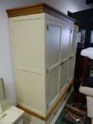 A MODERN OAK AND PAINTED PANELLED TRIPLE WARDROBE WITH A TWO DRAWER BASE AND SHAPED PLINTH. 172 x 60