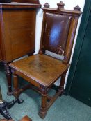 A PAIR OF VICTORIAN GOTHIC OAK HALL CHAIRS WITH UPHOLSTERED BACK PADS.