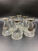 A SET OF SIX GLASS AND SILVER TOPPED WHISKEY TOTS WITH TWO ASSOCIATED WHISKEY LABELS, DATED 1921,