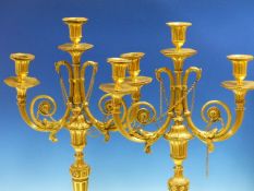 A PAIR OF ORMOLU NEOCLASSICAL THREE LIGHT CANDELABRA, THE FLUTED OCTAGONAL NOZZLES ABOVE BEAD EDGED