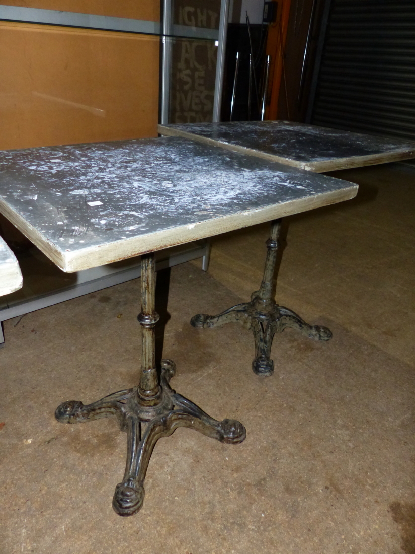 A PAIR OF VINTAGE CAFE TABLES WITH CAST IRON BASES AND ZINC WRAPPED PINE TOPS. 59 x 59 x H.73cms.