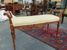 AN EDWARDIAN SATINWOOD AND INLAID WINDOW SEAT/STOOL WITH RAISED ARMS OVER CARVED AND FLUTED LEGS.