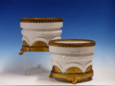 A PAIR OF ORMOLU MOUNTED WHITE PORCELAIN CACHE POTS, THE BEADED RIMS ABOVE FOLIAGE WREATHS CENTRAL