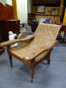 A GOOD QUALITY TEAK PLANTATION CHAIR WITH CANE SEAT AND SWING OUT LEG SUPPORTS.