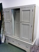 A MODERN PAINTED PINE TRIPLE DOOR WARDROBE WITH A TWO DRAWER BASE AND SHAPED BRACKET FEET. 166 x