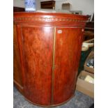 A GEORGIAN BOW FRONT CORNER CABINET.