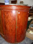 A GEORGIAN BOW FRONT CORNER CABINET.