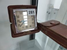 A SWISS TRAVEL CLOCK AND A SMALL CAMERA.