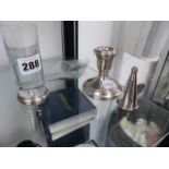 A SILVER MOUNTED SHOT GLASS, A CANDLESTICK, SILVER SNUFFER AND TWO CADDY SPOONS.