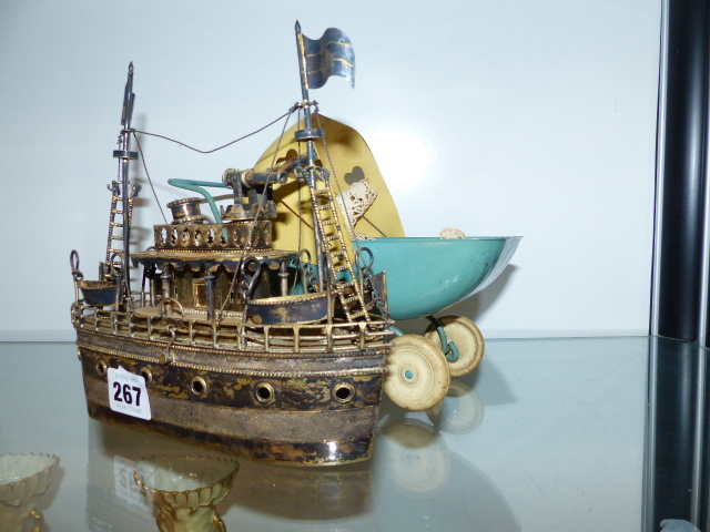 A WHITE METAL NOVELTY BATTLESHIP AND A TIN PLATE TOY PRAM.