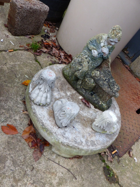 A CIRCULAR POT STAND ON CLAW FEET AND A GARDEN FIGURE.