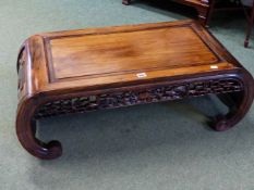 A CHINESE HARDWOOD COFFEE TABLE, THE NARROW ENDS CARVED WITH FLOWER HEADS AND CURVING INTO THE FEET,
