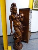 AN INDIAN CARVED HARDWOOD NEAR LIFE SIZE FIGURE OF A LADY CARRYING A WATER JAR, TWO GARLANDS