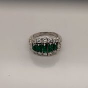 AN EMERALD AND DIAMOND DRESS RING DESIGNED AS A GRADUATED RECTANGLE -SHAPE EMERALD LINE A WITH