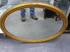 AN EDWARDIAN GILT OVAL WALL MIRROR IN REEDED FRAME. 62 x 86cms.