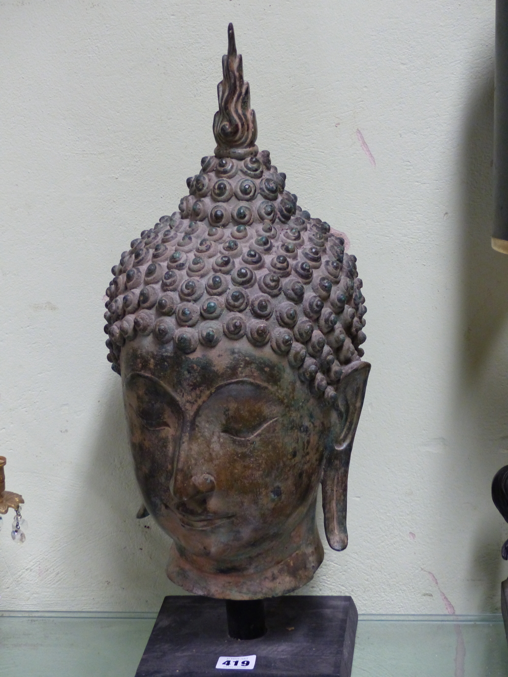 A THAI BRONZE HEAD OF THE BUDDHA, CURLED HAIR ABOVE HIS LONG LOBED EARS, HIS USNISA WITH FLAME