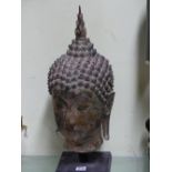 A THAI BRONZE HEAD OF THE BUDDHA, CURLED HAIR ABOVE HIS LONG LOBED EARS, HIS USNISA WITH FLAME