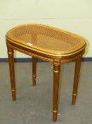 A CANED GILT WOOD STOOL, THE SEAT WITH ROUNDED ENDS ABOVE FLUTED TAPERING CYLINDRICAL LEGS. W 56 x D