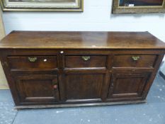 A GEORGIAN PINE DRESSER THE THREE DRAWERS WITH BRASS HANDLES ABOVE TWO CUPBOARDS FLANKING A