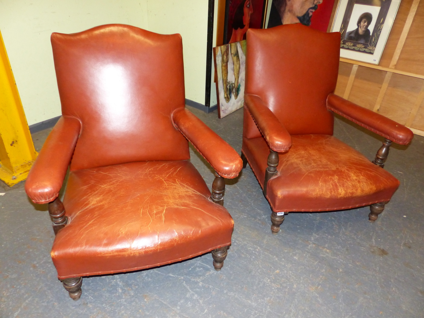 A PAIR OF RUST LEATHER UPHOLSTERED OAK ARMCHAIRS, THE PADDED ARM RESTS JOINED TO SERPENTINE TOPPED