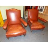 A PAIR OF RUST LEATHER UPHOLSTERED OAK ARMCHAIRS, THE PADDED ARM RESTS JOINED TO SERPENTINE TOPPED