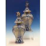 A PAIR OF DUTCH DELFT BLUE AND WHITE VASES WITH LEAF HANDLED COVERS, THE BODIES PAINTED ON ONE