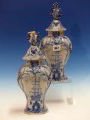 A PAIR OF DUTCH DELFT BLUE AND WHITE VASES WITH LEAF HANDLED COVERS, THE BODIES PAINTED ON ONE