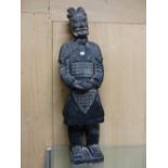 A CHINESE BLACKENED TERRACOTTA SOLDIER STANING WITH HIS HANDS CLASPED ON HIS LACQUER ARMOURED