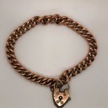 A 9ct OLD ROSE GOLD CURB LINK CHARM BRACELET COMPLETE WITH PADLOCK AND SAFETY CHAIN. WEIGHT 10.