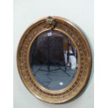 A BEVELLED GLASS OVAL MIRROR IN GILT WOOD FRAME. THE OUTER FOLIAGE BAND ENCLOSING A BLACK GROUND