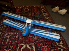 A SCALE MODEL BLUE AND WHITE PAINTED BIPLANE,THE PILOT IN THE REAR OF TWO COCKPITS BEHIND THE