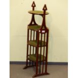 AN EDWARDIAN MAHOGANY FOUR TIER CAKE STAND, HEART SHAPED HANDLES RAISED ABOVE THE TOP TIER AND