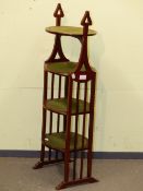 AN EDWARDIAN MAHOGANY FOUR TIER CAKE STAND, HEART SHAPED HANDLES RAISED ABOVE THE TOP TIER AND